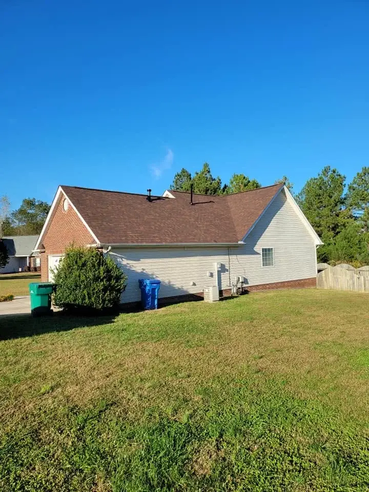 Side view of a finished shingle roof on a brick home